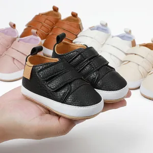 Detail of soft-soled infant walking shoes in multiple colors held in hand for scale