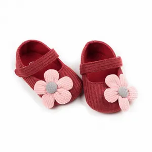Detail of wine red knitted baby walking shoes with a soft pink floral appliqué