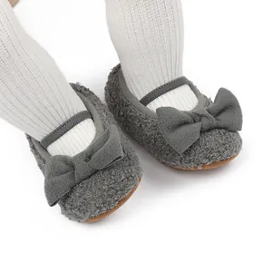 Primer plano de zapatos de bebé en felpa gris con lazo y suela blanda para invierno.