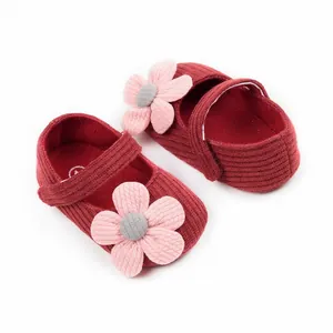 Close-up detail of red knitted baby girl walker shoes with decorative pink flowers