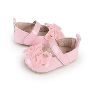 Detalle del charol rosa y el lazo de terciopelo de estos zapatos de bebé niña real.