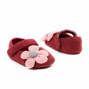 Detailed texture of red knitted baby girl princess shoes with pink flower decoration