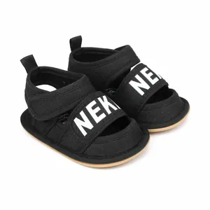 Detail view of black canvas baby walker sandals with white NEK print and velcro closure