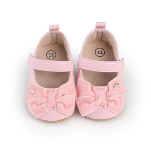 Detalle de zapatos de princesa rosa para bebé con lazo de terciopelo y dorado