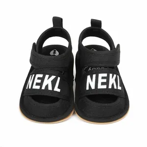 Detailed front view of black baby summer walking sandals with white NEKL text straps