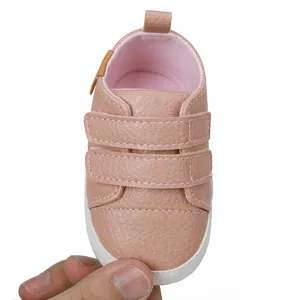Close-up detail of pink baby walking shoe with double velcro straps on white background