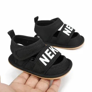 Close-up of black breathable infant summer walking sandals held in hand for size reference