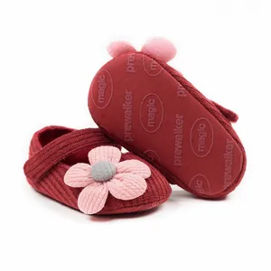 Close-up view of red knit baby walker shoes with a soft sole and a decorative pink flower.
