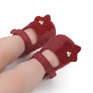 Dettaglio ravvicinato di scarpine per neonati in maglia rossa con fiori e perle.