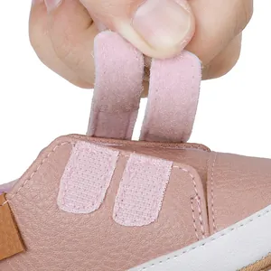 Detailed close-up of double velcro straps on pink infant walking shoes for easy wear.