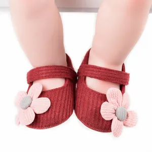 Close-up of red knitted baby girl pre-walker shoes with pink flowers