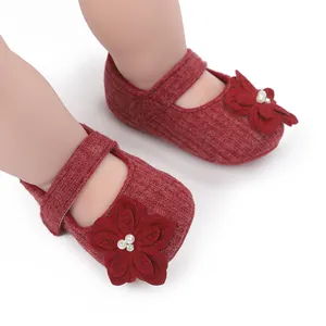 Vista dettagliata di scarpine da neonata rosse con fiori 3D e dettagli in perle