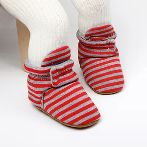 Gros plan détaillé de bottines d'hiver à rayures rouges et grises sur un mannequin bébé