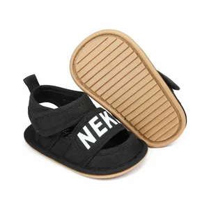 Detailed view of the anti-slip tan sole and velcro strap on black infant walking sandals
