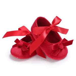 Vue détaillée de chaussures bébé en velours rouge avec d'élégants nœuds en satin