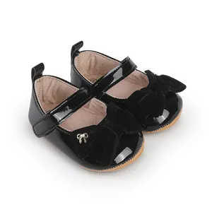 Detalle de zapatos de princesa para bebé en charol negro con lazo de terciopelo