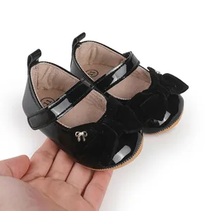 Detalle de zapatos de princesa para bebé en charol negro con un elegante lazo de terciopelo