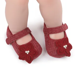 Primo piano di scarpine rosse da principessa per neonati con grande fiore 3D e perla.