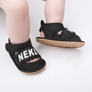Detail of black baby sandals with white NEKL lettering and a flexible non-slip sole