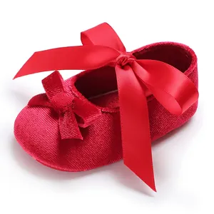 Vue détaillée d'un soulier de bébé en velours rouge orné d'un gros nœud satin