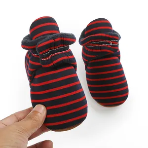 Détail des bottes d'hiver pour bébé avec rayures rouges et bleues et doublure polaire.