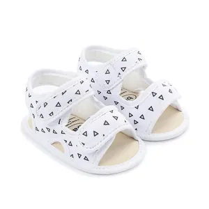 Detailed view of white baby sandals with black triangle patterns and adjustable straps