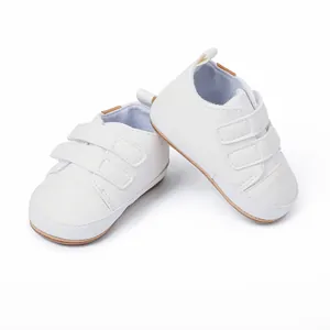 Detail of white infant walking shoes with double hook-and-loop straps and soft soles.