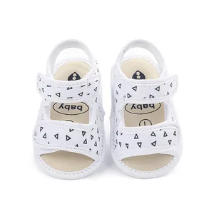 Detail of white baby walking sandals with black triangle patterns and soft non-slip soles.