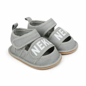 Close-up detail of grey baby walking sandals with white letter print and Velcro straps