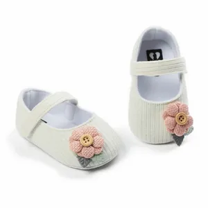 Detail der Strickblume und der weichen Textur der weißen Baby-Prinzessin-Schuhe
