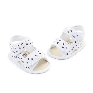 Close-up of white baby sandals with black triangle patterns and soft soles