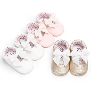 Primer plano de zapatos de bebé princesa con lazos en colores rosa blanco y dorado