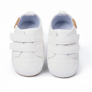 Top-down view of white baby walking shoes with dual hook and loop straps