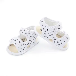 Close-up of white baby walking sandals with black triangle pattern and velcro straps.