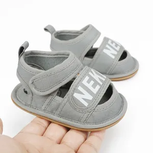 Close-up detail of grey canvas baby sandals with velcro strap and white letter print