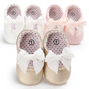 Primer plano de adorables zapatos de princesa para bebé con lazos en oro, blanco y rosa