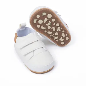 Close-up detail of white infant walking shoes showing non-slip sole and Velcro straps