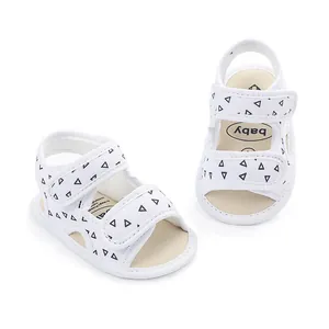 Macro view of white baby walking sandals featuring black triangle print and soft sole