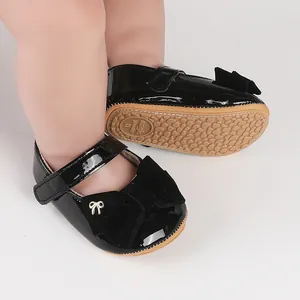 Primer plano de zapatos de princesa para bebé en charol negro con lazo de terciopelo.