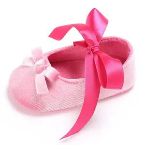 Gros plan d'une chaussure de bébé en velours rose avec nœud en satin et semelle souple