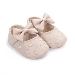 Detail von rosa Baby-Prinzessin-Schuhen mit Herzstickerei und dekorativer Schleife