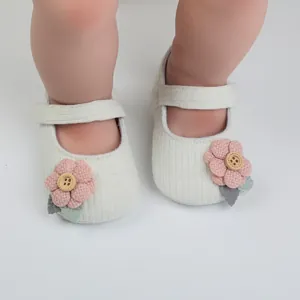 Detailansicht weißer gestrickter Baby-Prinzessin-Schuhe mit rosa Stoffblumen-Deko.