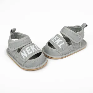 Macro view of gray baby summer sandals with white NEKL text and velcro straps