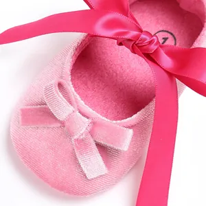 Détail de chaussures de bébé en velours rose avec de grands nœuds en ruban de satin