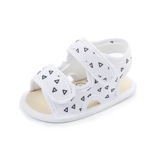 White baby summer walking sandals with black triangle patterns and dual velcro straps