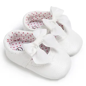 Detalle de zapatos de princesa para bebé blancos con lazo y forro de lunares