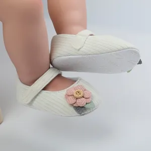 Detailaufnahme weicher Strick-Babyschuhe für Mädchen mit rosa Blume und Holzknopf-Akzent