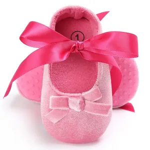 Gros plan de chaussures de bébé en velours rose avec un grand nœud en ruban de soie