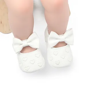 Makro-Detailansicht weißer Baby-Prinzessinenschuhe mit großen Schleifen und Herzmustern