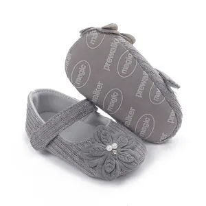 Dettaglio scarpe neonato grigie con suola morbida e decorazione di fiori e perle